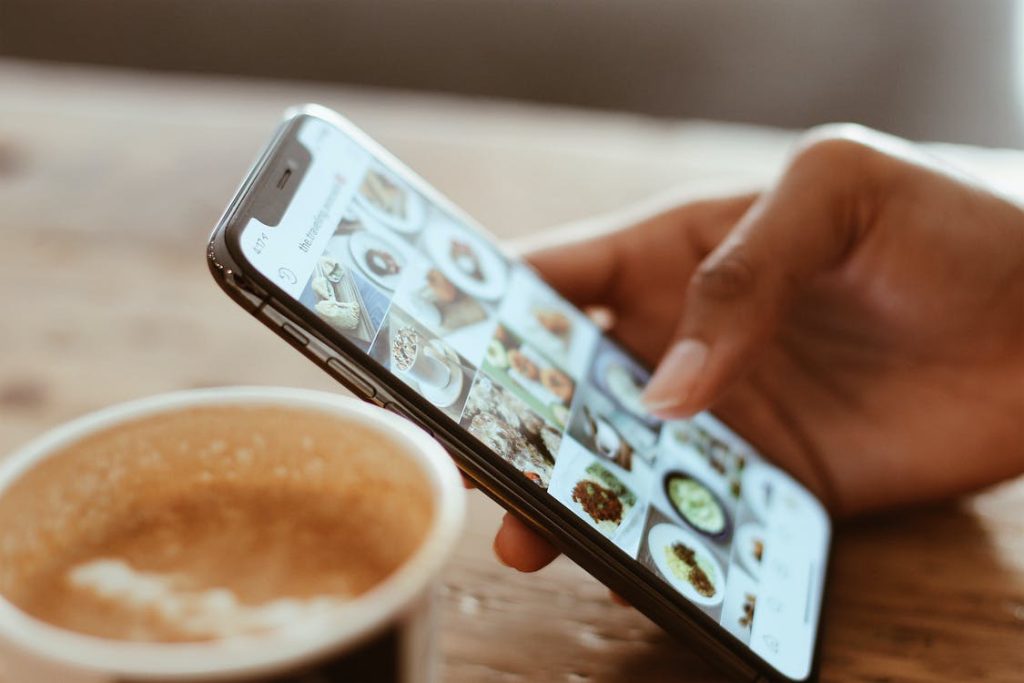 A person scrolls through an Instagram profile with pictures and videos of food.