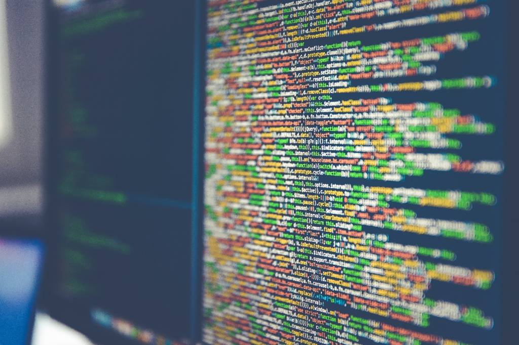 A computer monitor shows colorful code