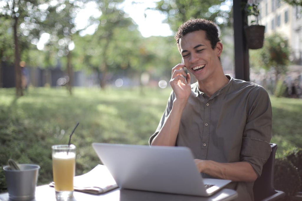 An image of a cheerful man talking on the phone while sitting outdoors