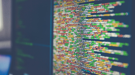 A computer monitor shows colorful code