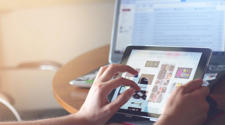 An image of a woman using tablet and laptop