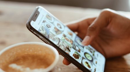 A person scrolls through an Instagram profile with pictures and videos of food.