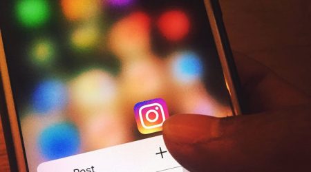 A person touches the Instagram app icon on their iPhone opening the dropdown menu